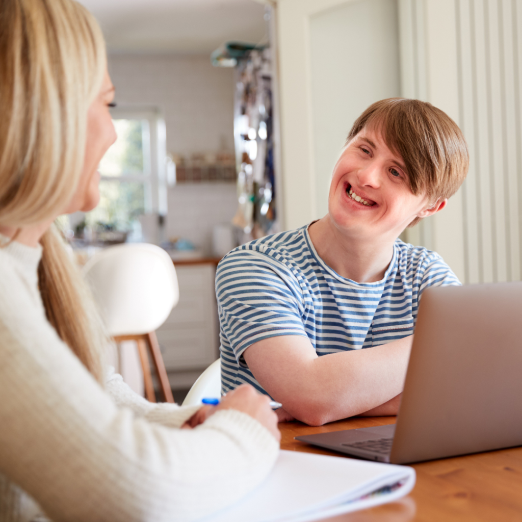 male disabled participant smiling while working with disability support worker