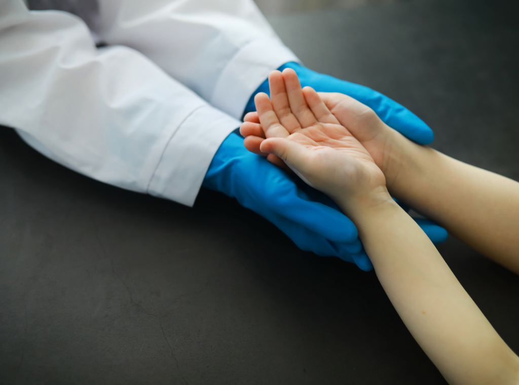Doctor wearing blue gloves holding young patients hands