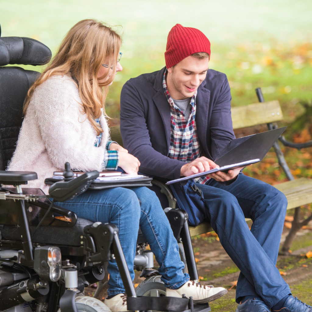 Allied Health Worker showing a client in a wheelchair something on a tablet